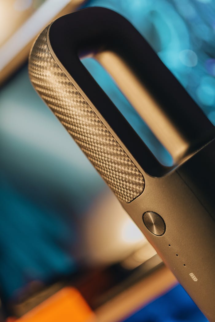 Stylish handheld vacuum cleaner with a carbon fiber handle and modern design.