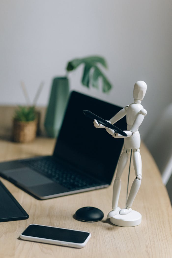 Modern workspace featuring a laptop, figurine, and smartphone on a wooden table.