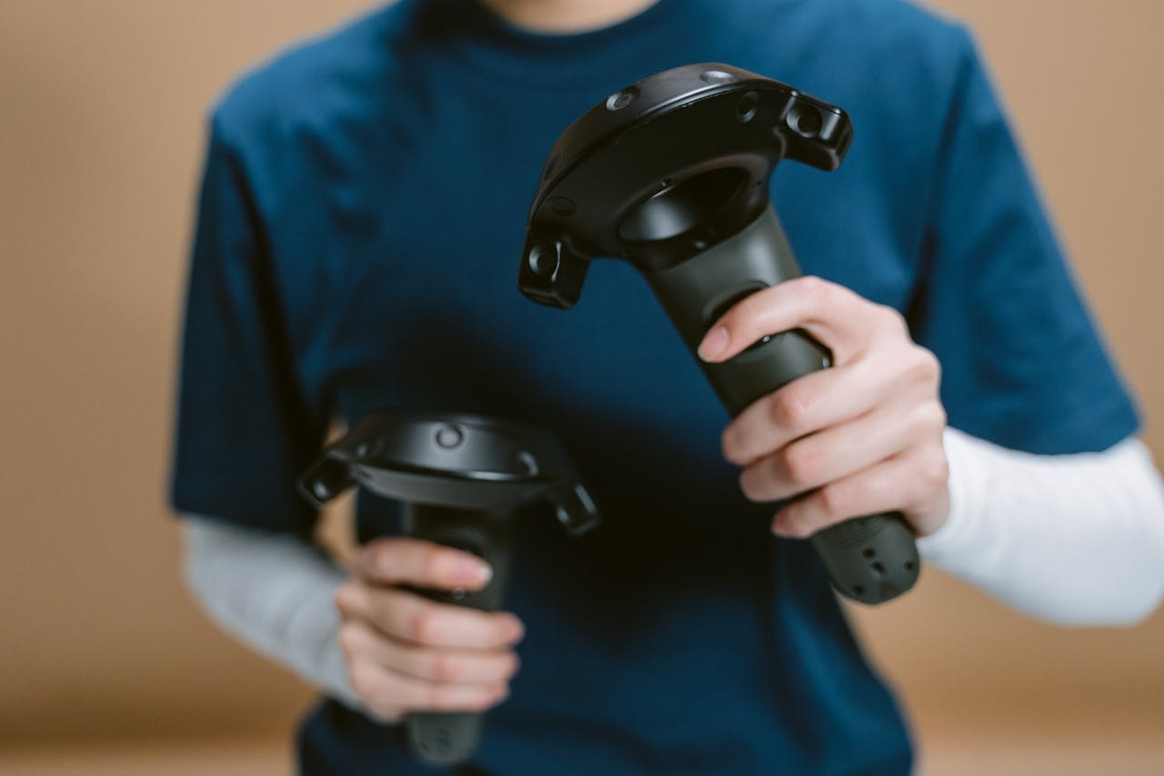 Close-up of individual holding VR controllers, focused on hands and devices.