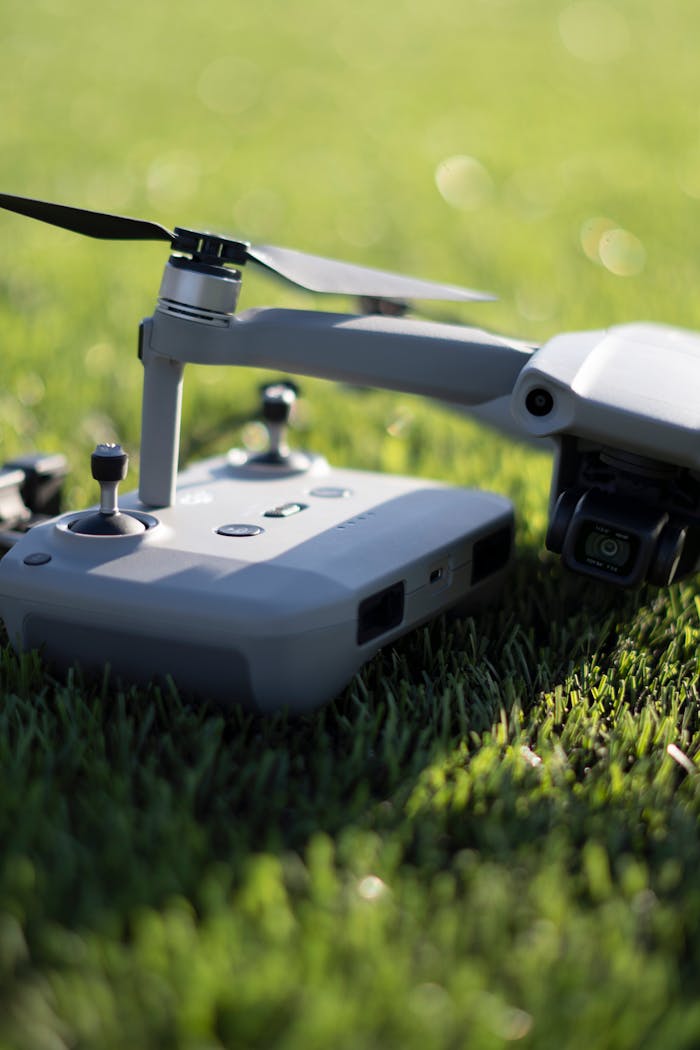 Close-up of a modern drone with controller placed on a vibrant green lawn, showcasing technology outdoors.